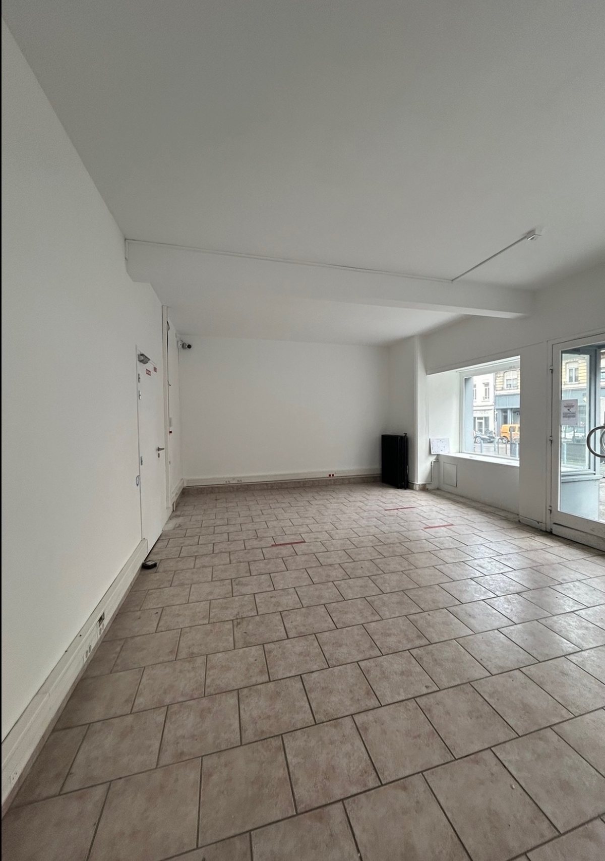 Le nouveau local avant les travaux : pièce vide, carrelage et vitrine