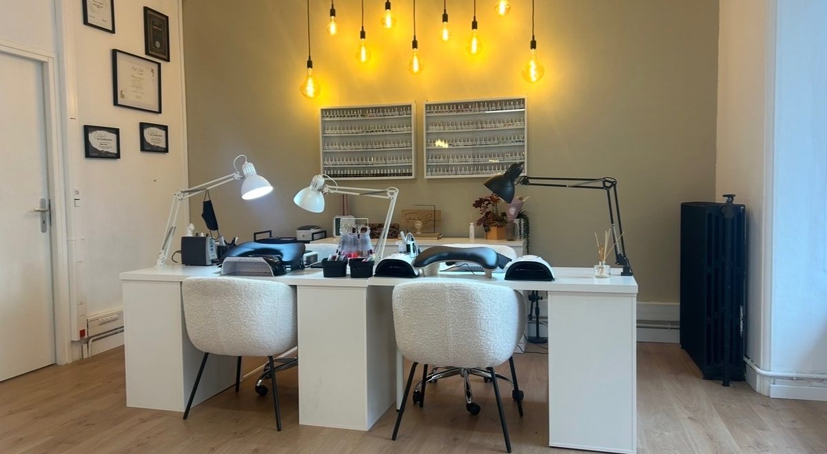 La salle de manucure avec deux postes, fauteuils bouclette et ampoules suspendues