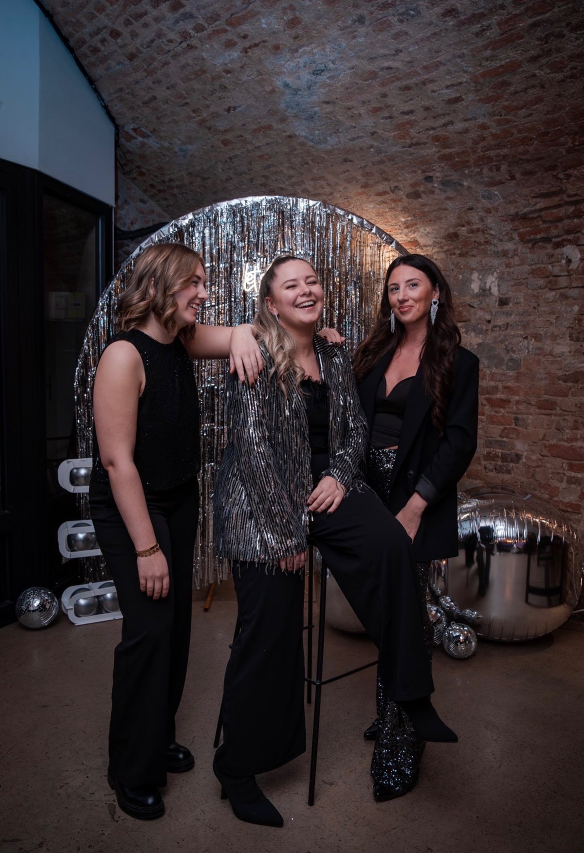 Justine et deux filles de l’équipe éclatent de rire devant le rideau argenté