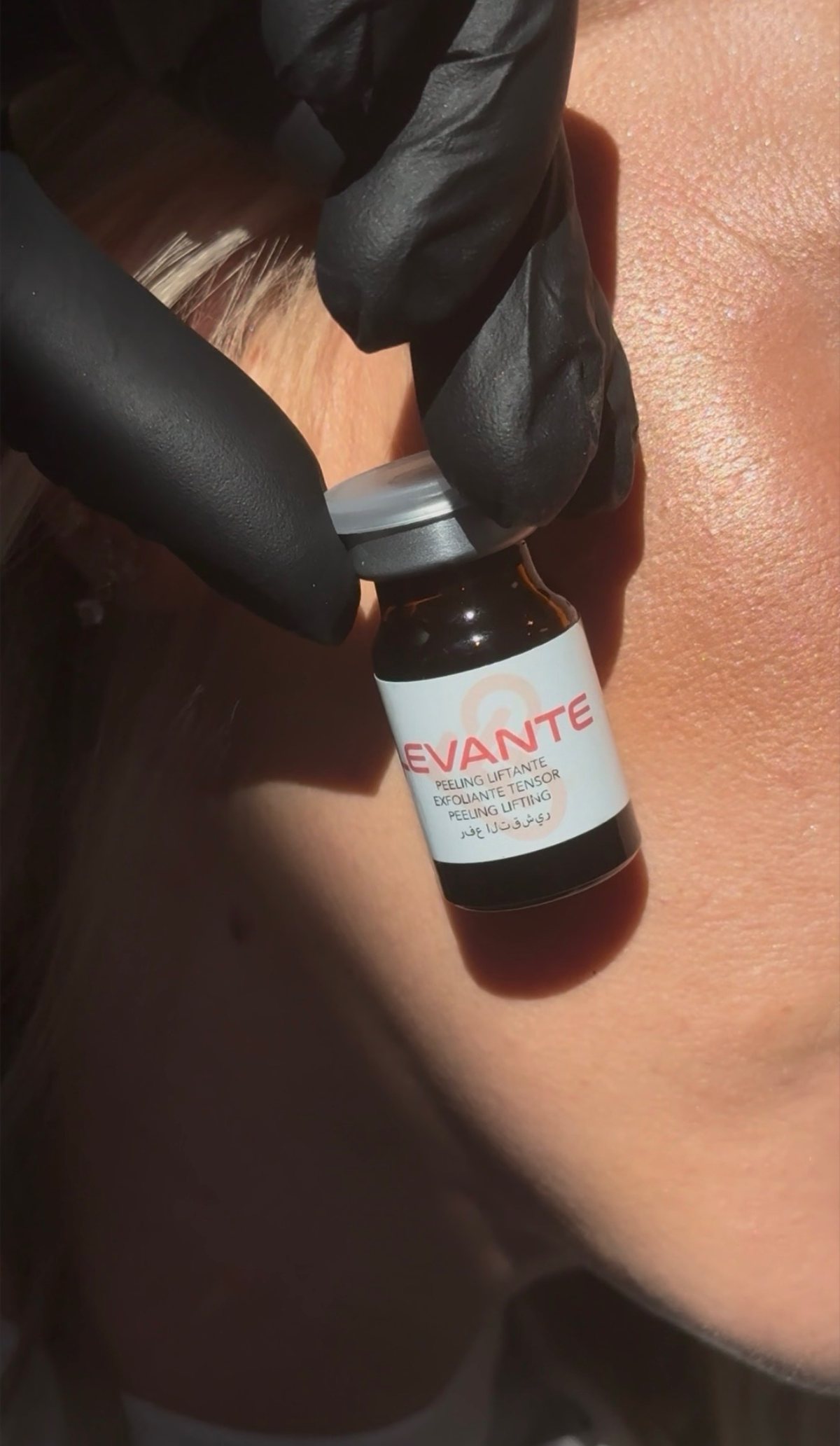 Un flacon de peeling Levante tenu par une main gantée
